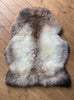 Grey and brown sheepskin rug on wooden for
