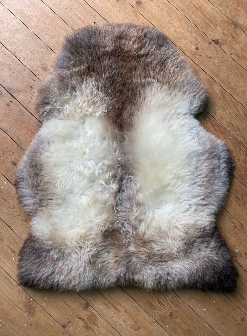 Grey and brown sheepskin rug on wooden for