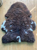 Brown sheepskin rug laid flat on wooden floor 