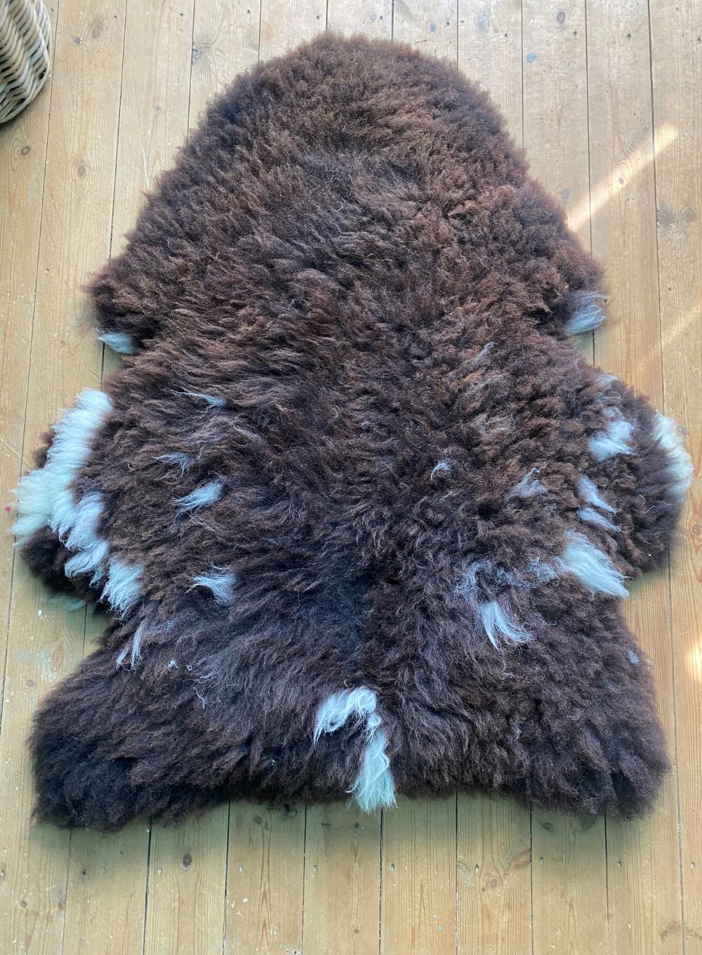 Brown sheepskin rug laid flat on wooden floor 