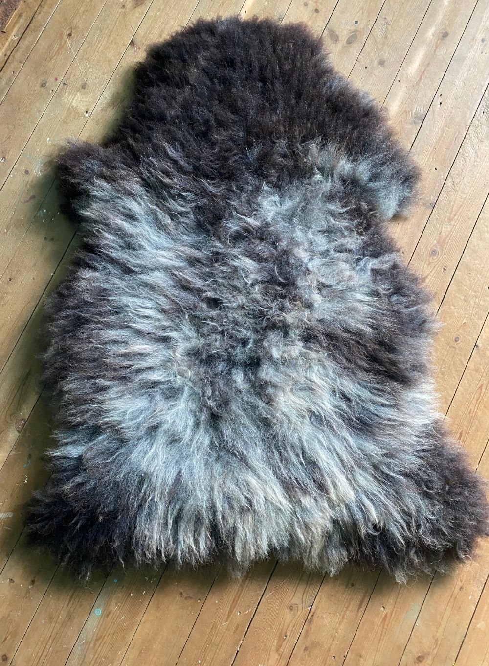 Grey sheepskin rug on wooden floor
