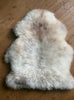 Cream speckled sheepskin rug on wooden floor