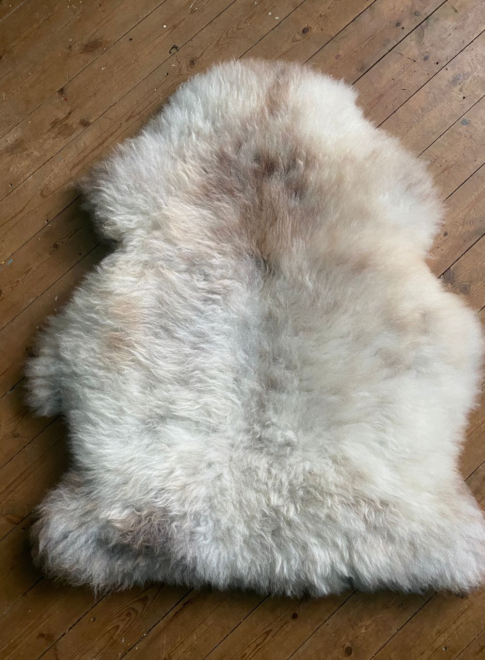 Cream speckled sheepskin rug on wooden floor