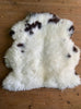 Cream and brown sheepskin rug on wooden floor 