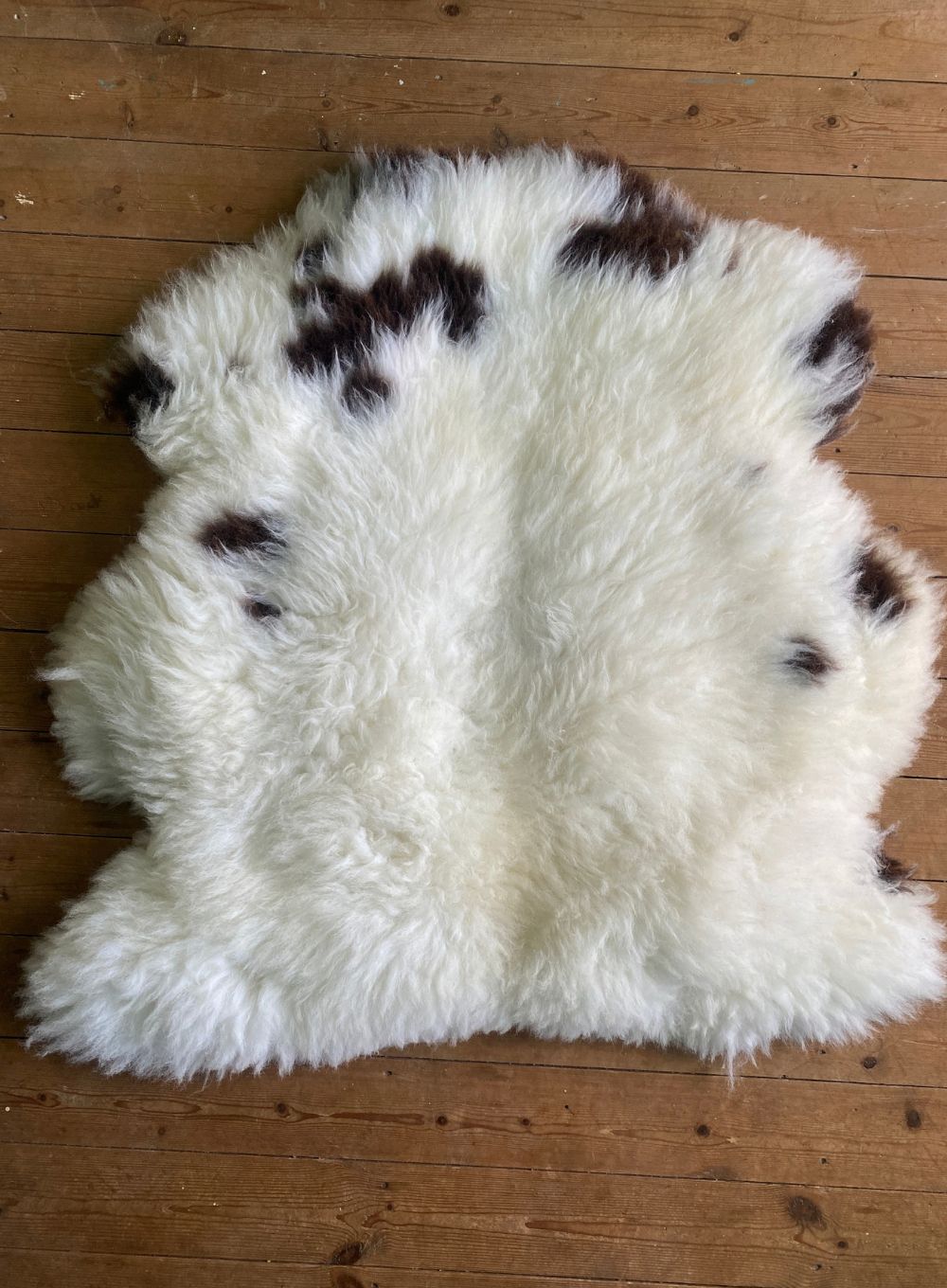 Cream and brown sheepskin rug on wooden floor 