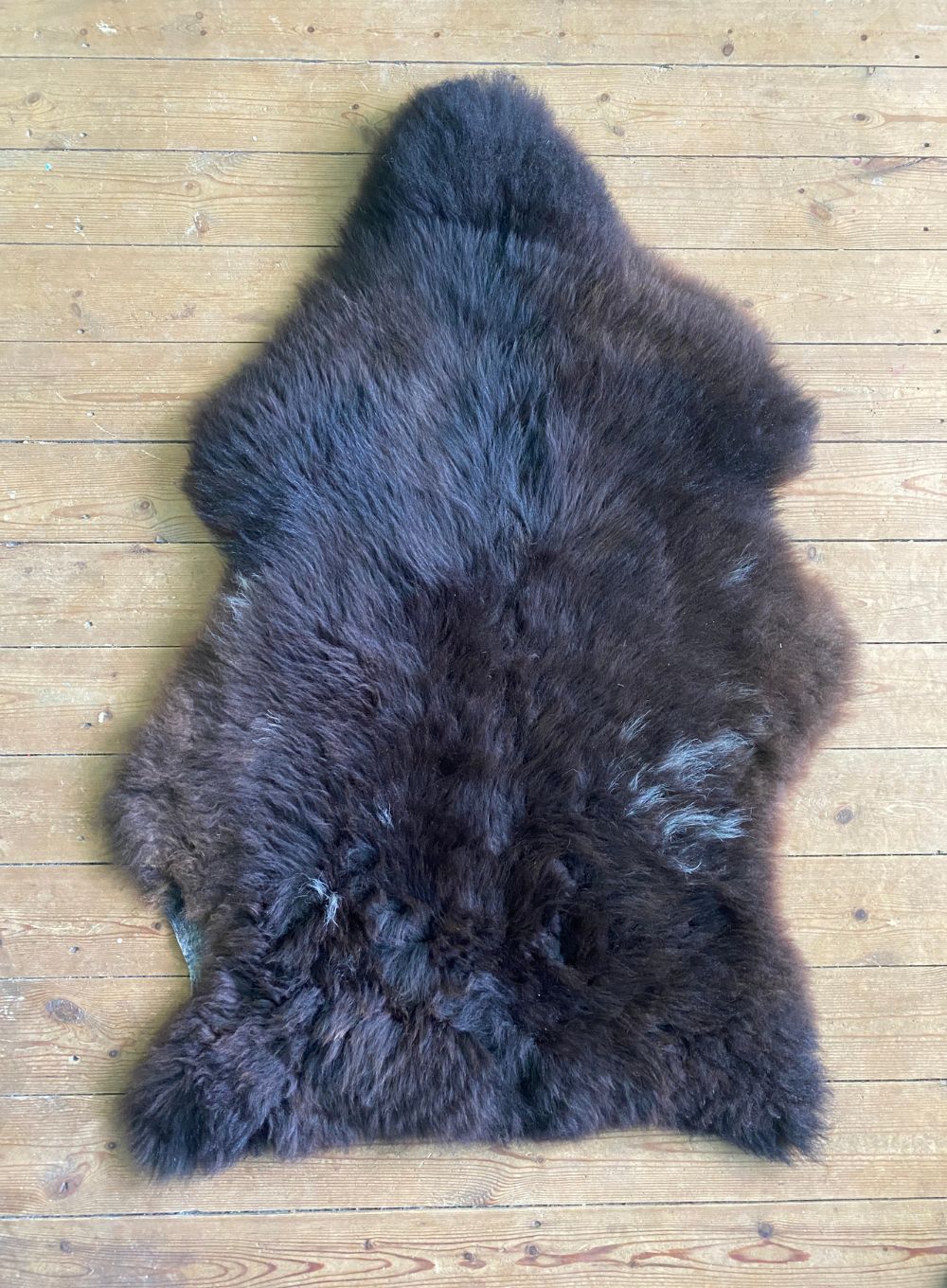 Brown sheepskin rug laid flat on wooden floor
