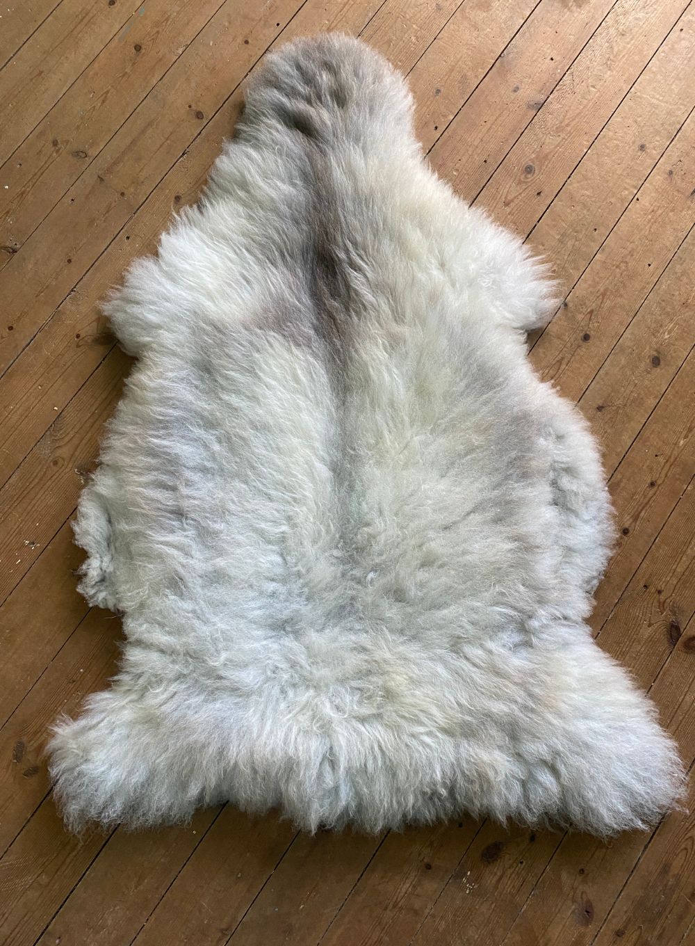 Cream sheepskin rug on wooden floor 