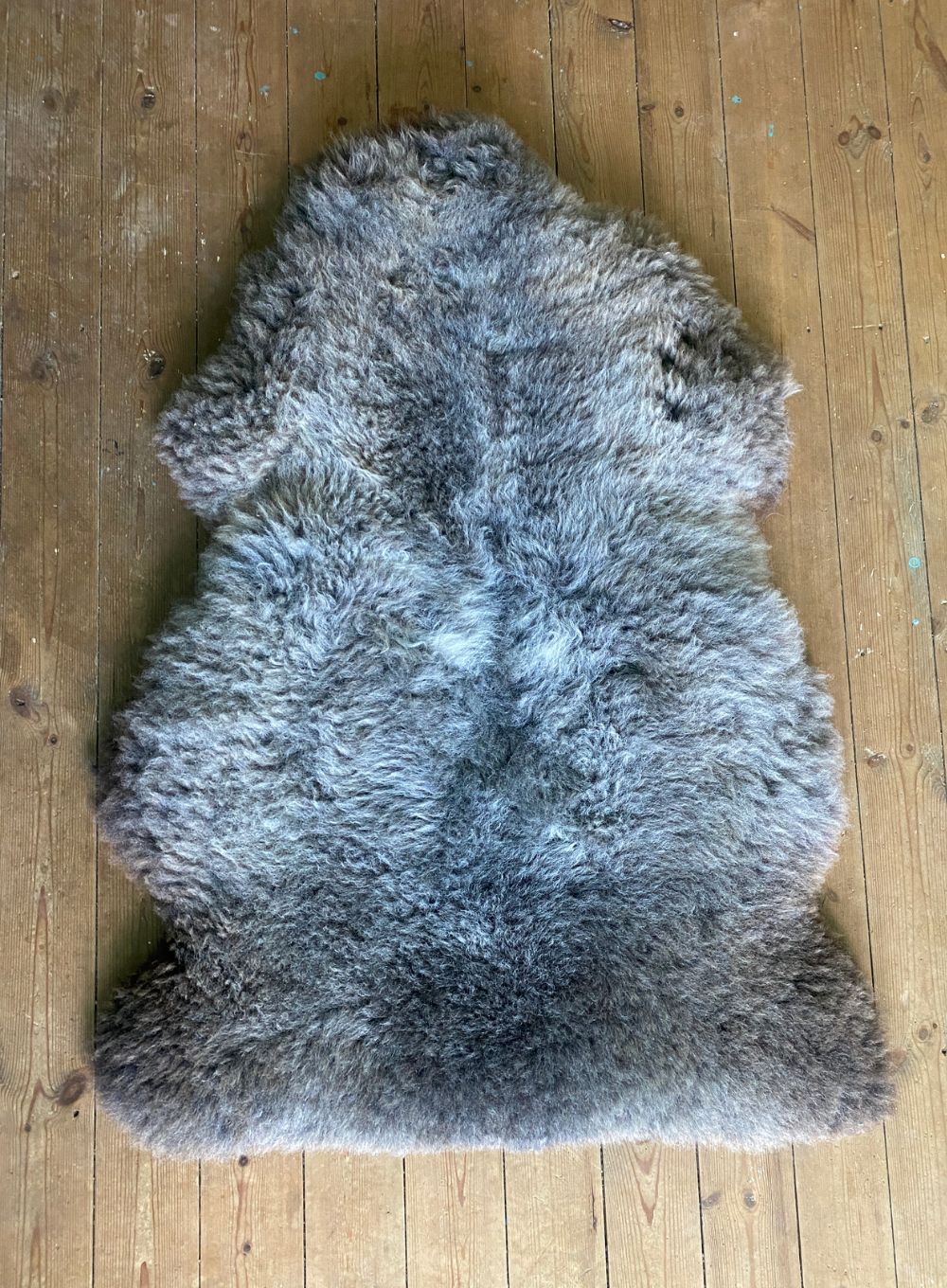 Brown and grey sheepskin rug on wooden floor