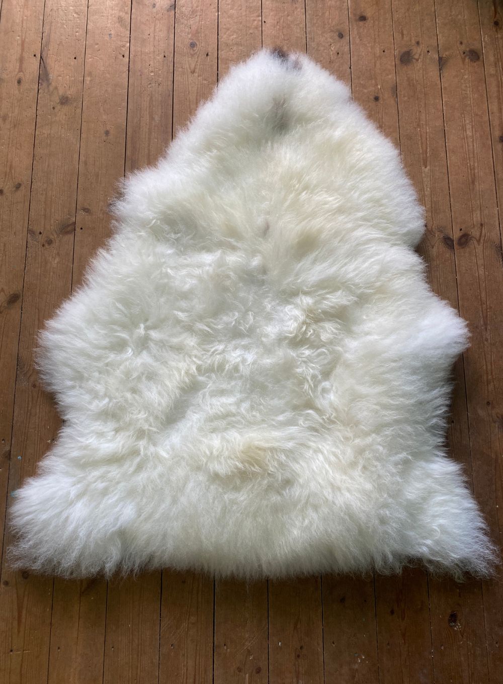 Cream sheepskin rug on wooden floor