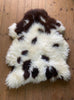 Brown and cream spotty sheepskin rug on wooden floor