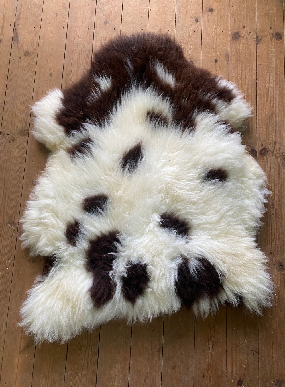 Brown and cream spotty sheepskin rug on wooden floor