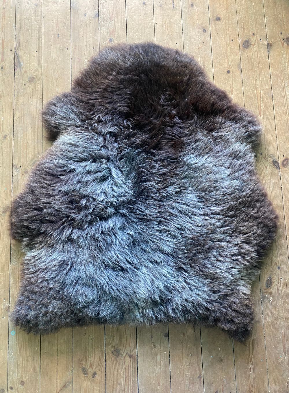Brown and grey sheepskin rug on wooden floor 