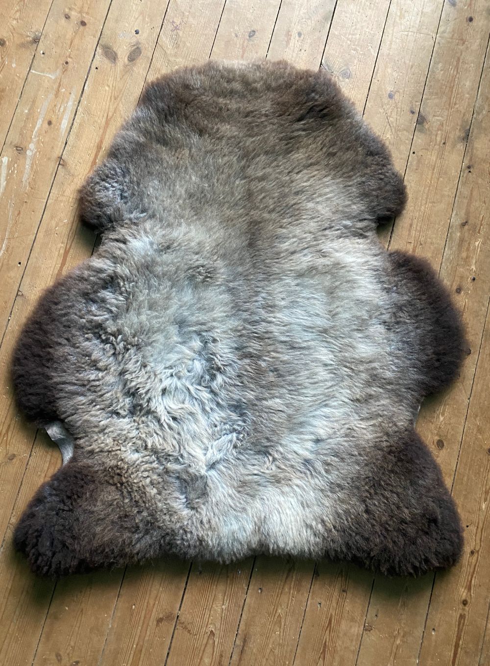 Grey and brown sheepskin rug  on wooden floor 