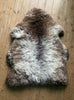 Grey and brown sheepskin rug on wooden floor 
