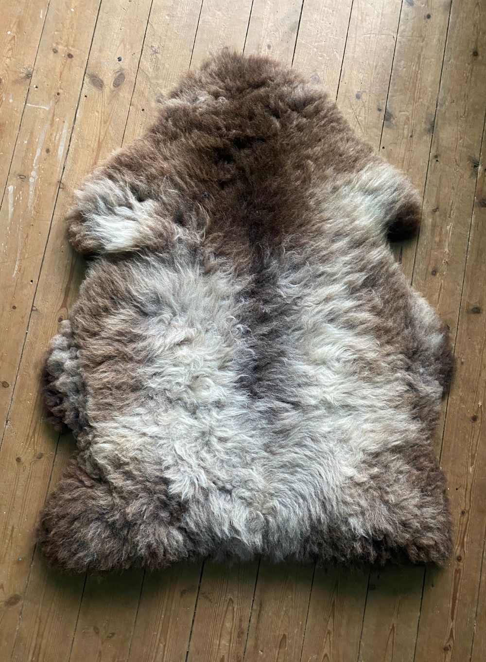Grey and brown sheepskin rug on wooden floor 