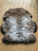 Grey and brown sheepskin rug on wooden floor 