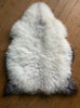 Cream speckled sheepskin rug on wooden floor 