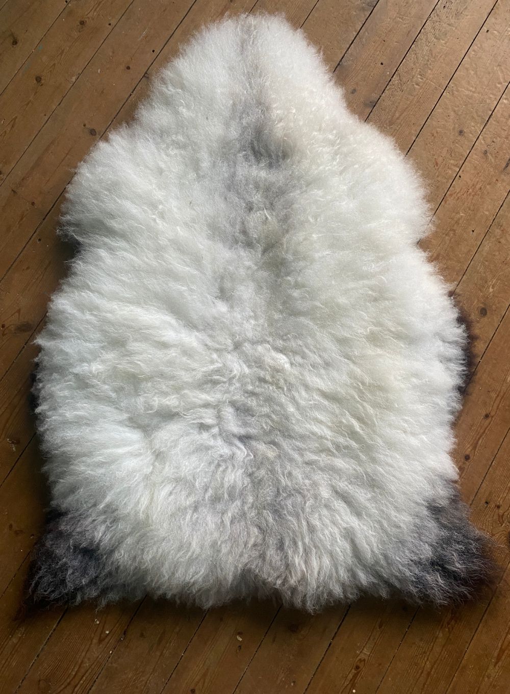 Cream speckled sheepskin rug on wooden floor 