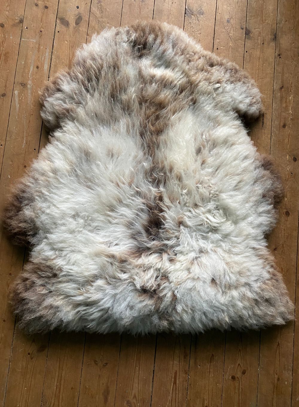 Speckled sheepskin rug on wooden floor