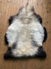 Cream speckled sheepskin rug on wooden floor 