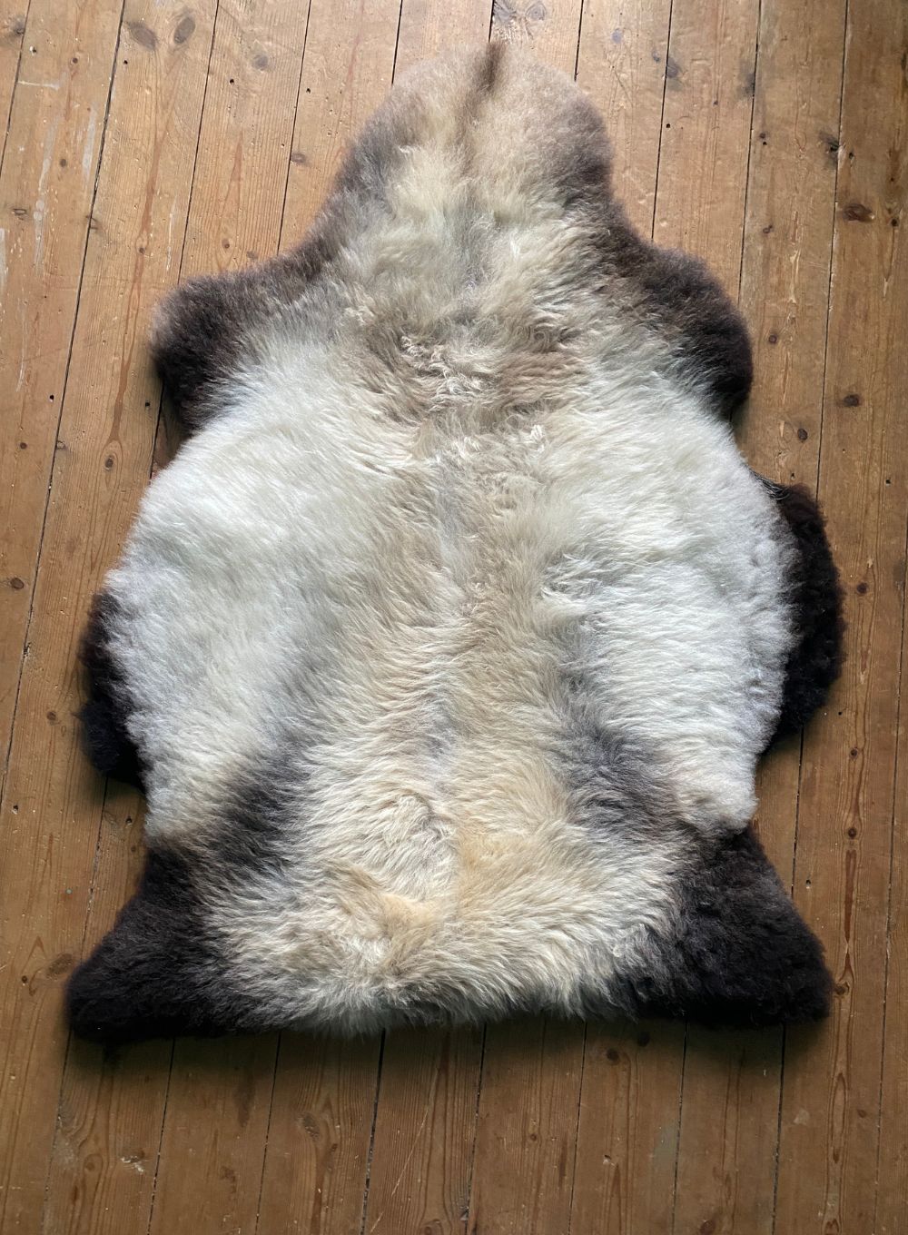 Cream speckled sheepskin rug on wooden floor 