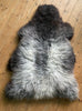 Grey sheepskin rug laid flat on wooden floor