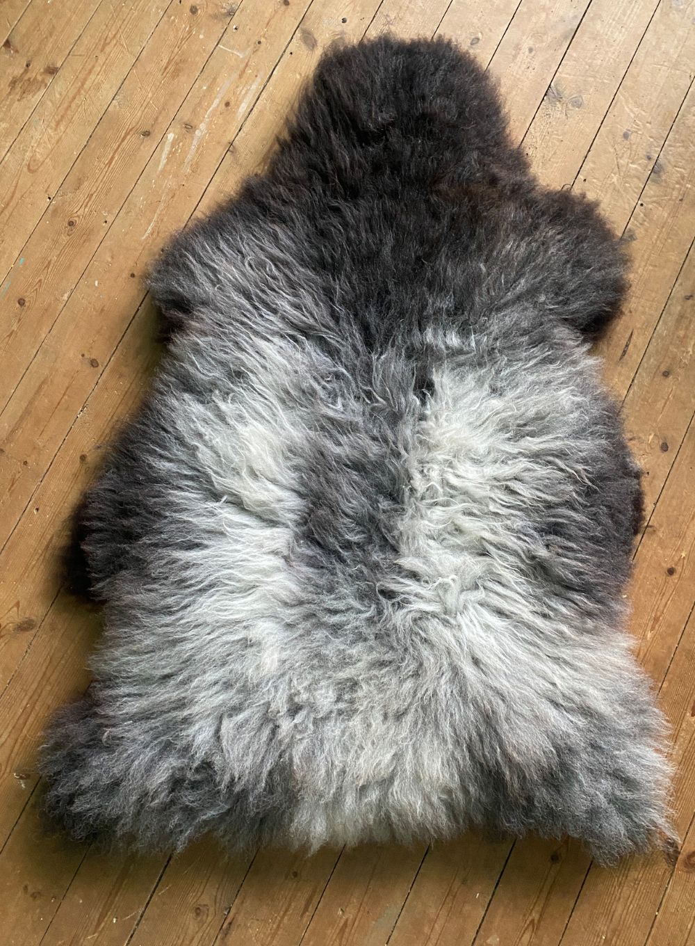 Grey sheepskin rug laid flat on wooden floor