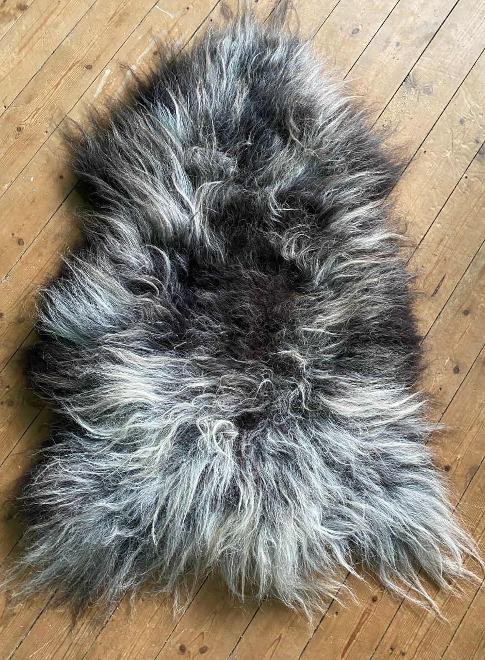 Grey and cream sheepskin rug on wooden floor