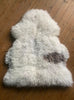 Cream sheepskin rug with brown spot on wooden floor 