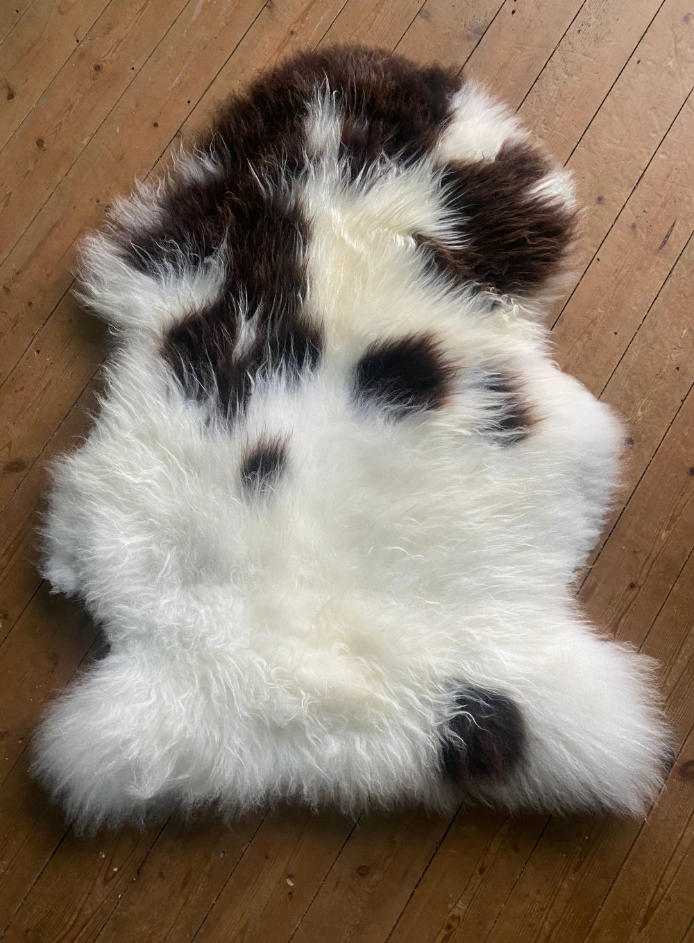 Brown and cream sheepskin rug on wooden floor 