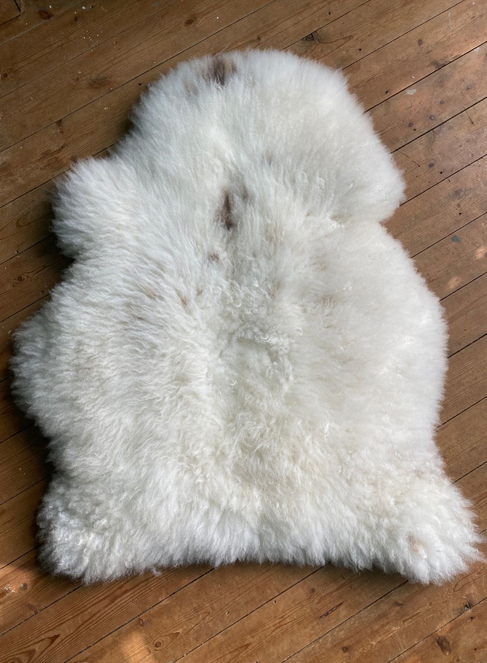 Cream sheepskin rug on wooden floor