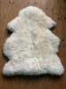 Cream sheepskin rug on wooden floor 