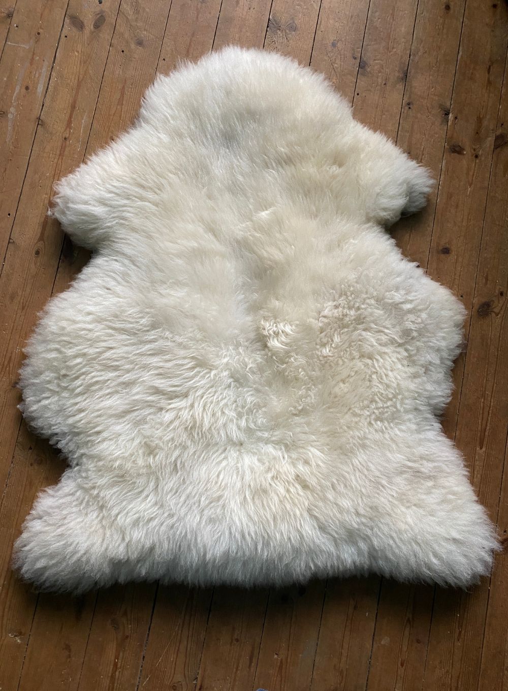 Cream sheepskin rug on wooden floor 