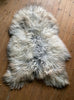 Grey and cream long haired sheepskin rug on wooden floor