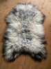 Grey and cream long haired sheepskin rug on wooden floor