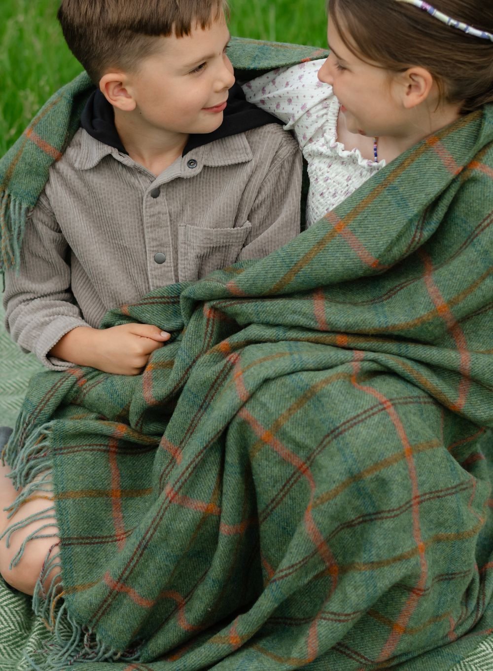 Two children wrapped in wool blanket 