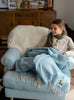 Girl wrapped in blanket on armchair